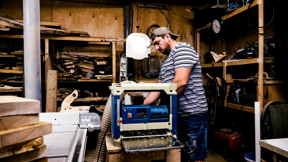 A carpenter is working with a machine at wood workshop