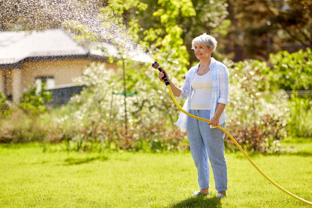 A senior woman watering the lawn