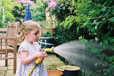 a blonde kid watering the garden